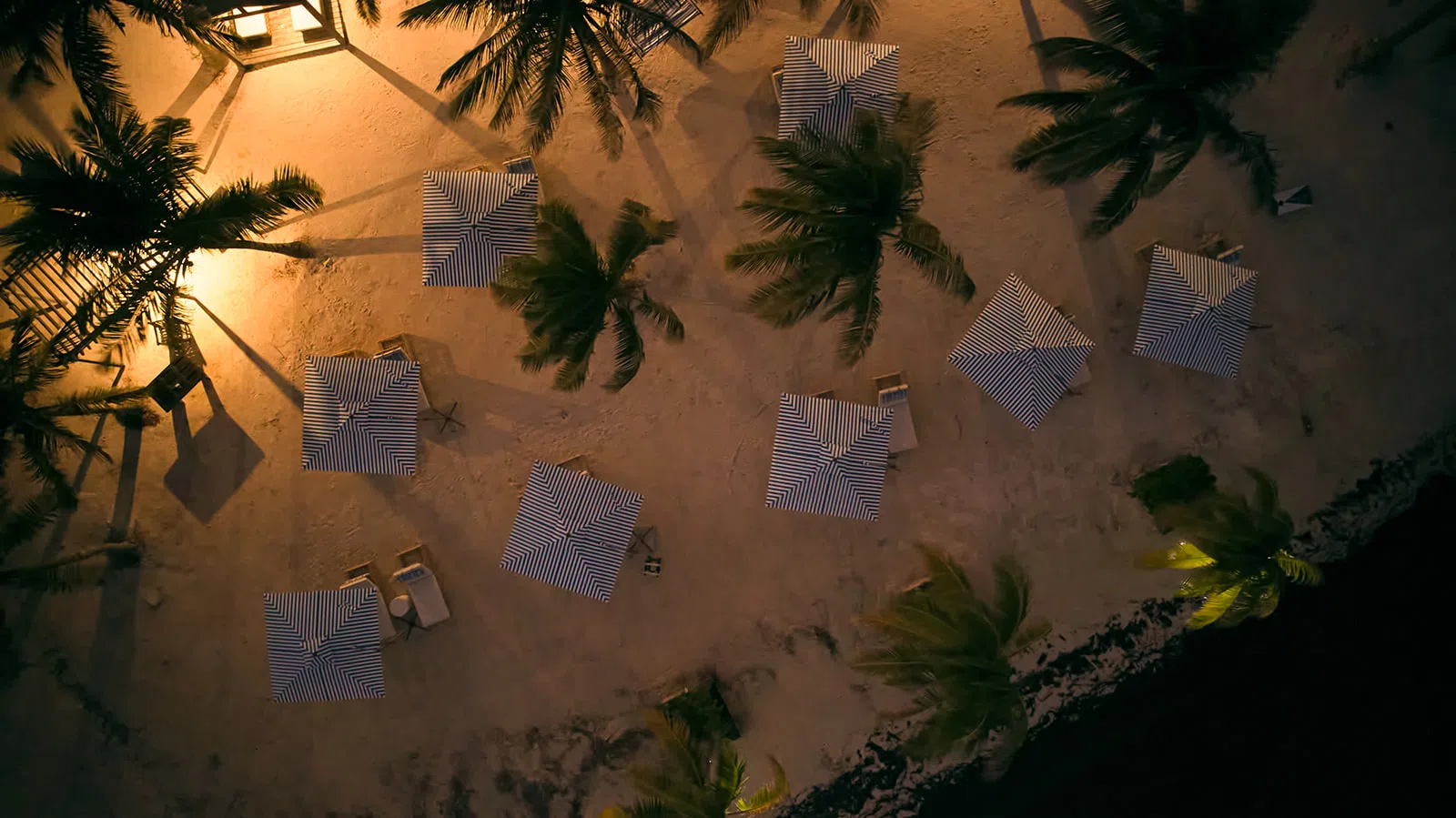 Private beach dinner setup with tiki torches and a candlelit table on the sand